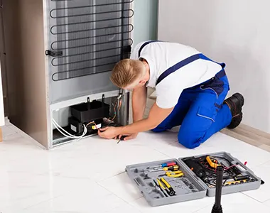 Technician inspecting refrigerator compressor